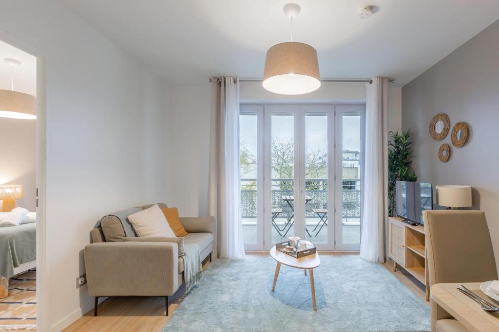 un salon avec un canapé et une télévision dans l'établissement OVELIA Ermont - Le Pavillon d'Amélie, à Ermont