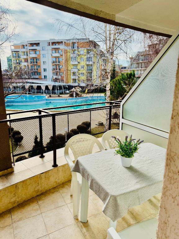 a balcony with a table and chairs and a swimming pool at Charming 2-bed flat with pool view in Sunny Beach, Bulgaria in Sunny Beach