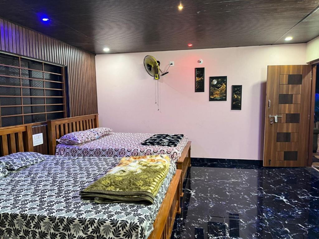 a room with two beds and a fan on the wall at Ocean pearl 01 in Kāsarkod