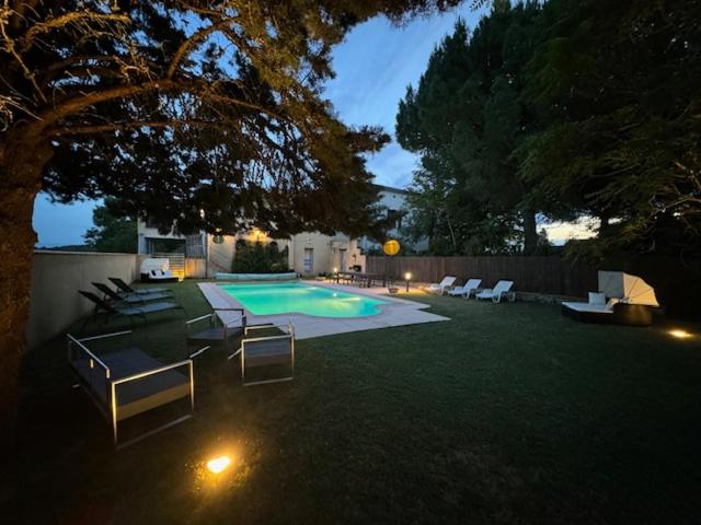 a backyard with a swimming pool with chairs and a tree at Belle Lauragaise ensoleillée in Issel