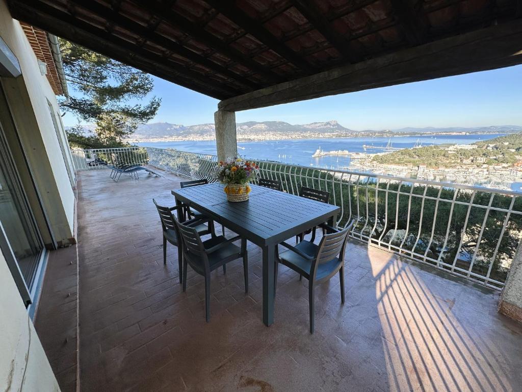 une table et des chaises sur un balcon avec vue sur l'eau dans l'établissement Haut de villa, pleine vue mer, à Saint-Mandrier-sur-Mer