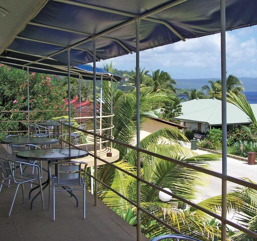 a patio with tables and chairs and the ocean at VQ3 Lodge in Flying Fish Cove