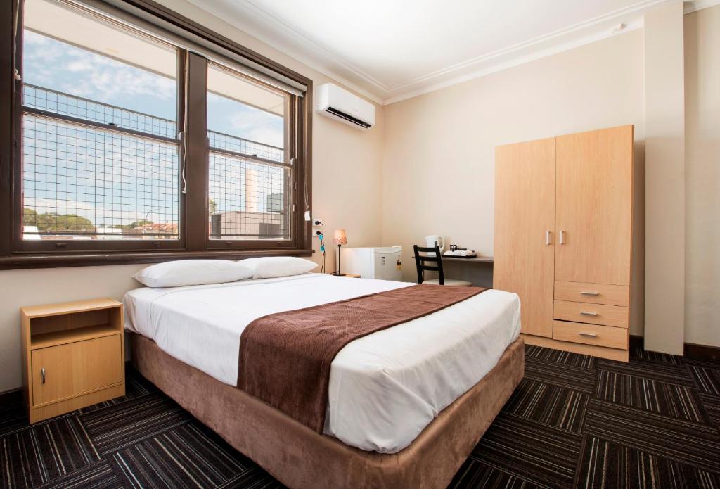 a bedroom with a large bed and two windows at Toongabbie Hotel in Blacktown