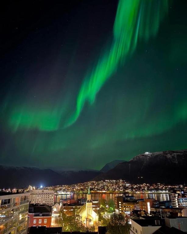 an image of the northern lights in the sky over a city at Sentrumsnær enebolig in Tromsø