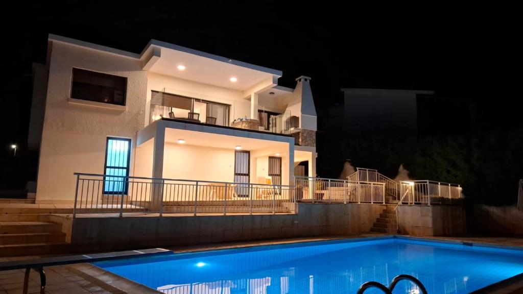 ein Haus in der Nacht mit Pool davor in der Unterkunft Panoramic Seacave Cottage in Peyia