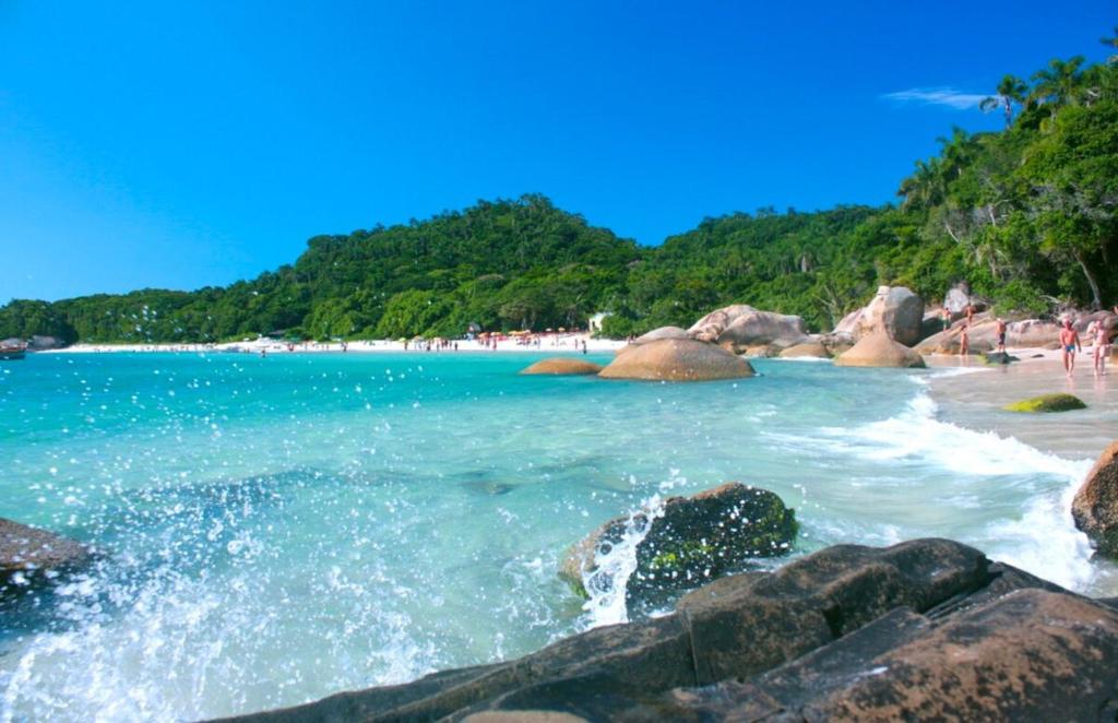 a beach with rocks and people on the beach at Ampla Casa Sul da Ilha in Florianópolis