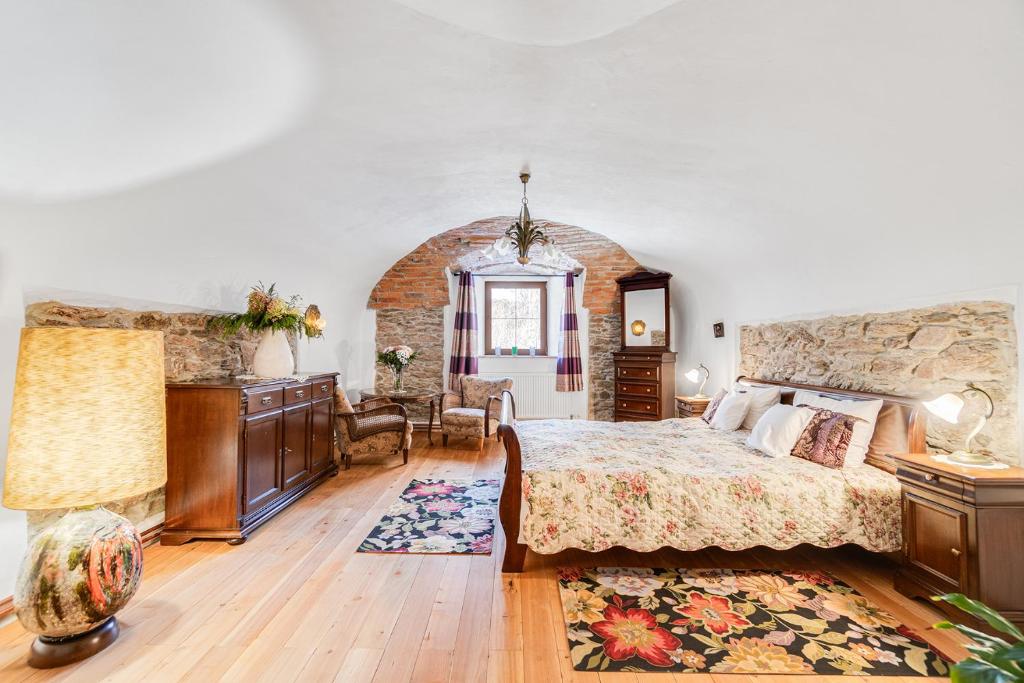 a bedroom with a large bed and a stone wall at Gościniec Śliwkowy Sad in Międzylesie