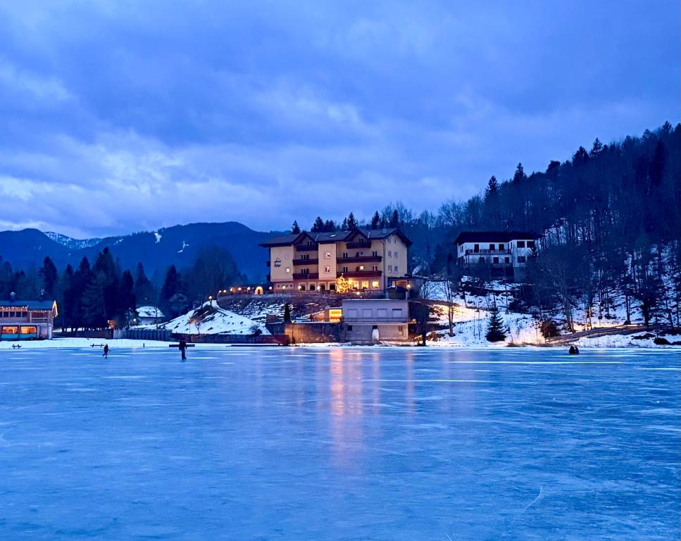 een huis aan de oever van een meer met sneeuw bij Hotel Al Lago in Lavarone