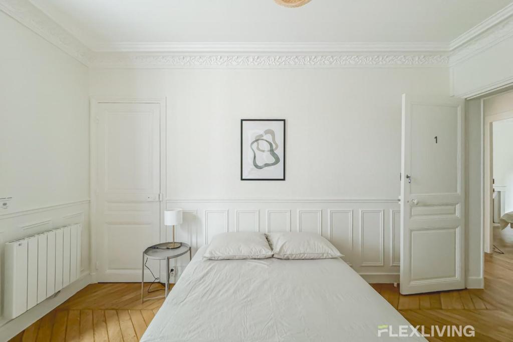 une chambre blanche avec un lit et une table dans l'établissement Flexliving - whole house - Hoche, à Levallois-Perret