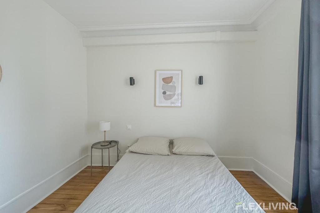 une chambre blanche avec un lit et une table dans l'établissement Flexliving - whole house - Gabriel Peri, à Levallois-Perret
