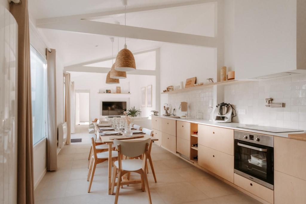 une cuisine blanche avec une table et des chaises dans l'établissement Charmant appartement à la décoration cosy - 2 personnes, à Les Sables-dʼOlonne