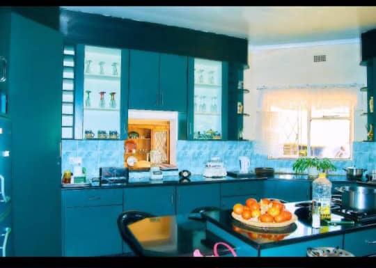una cucina blu con una ciotola di arance su un tavolo di Baobab Garden a Harare