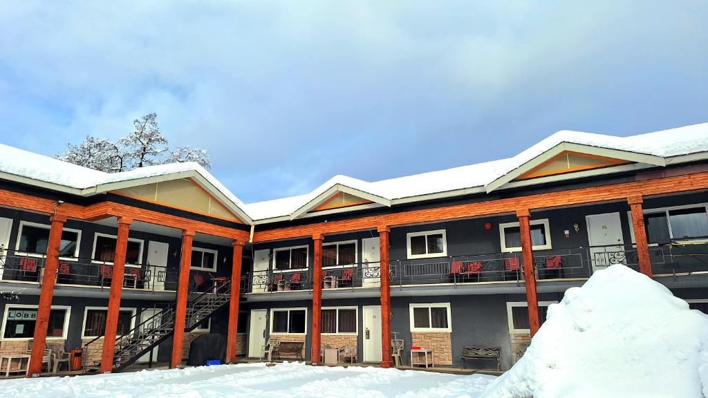 an apartment building with snow on the ground at Alpine Inn & Suites in Revelstoke