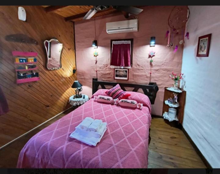 a bedroom with a pink bed with two towels on it at Cabaña 'Te para Tres' in Merlo