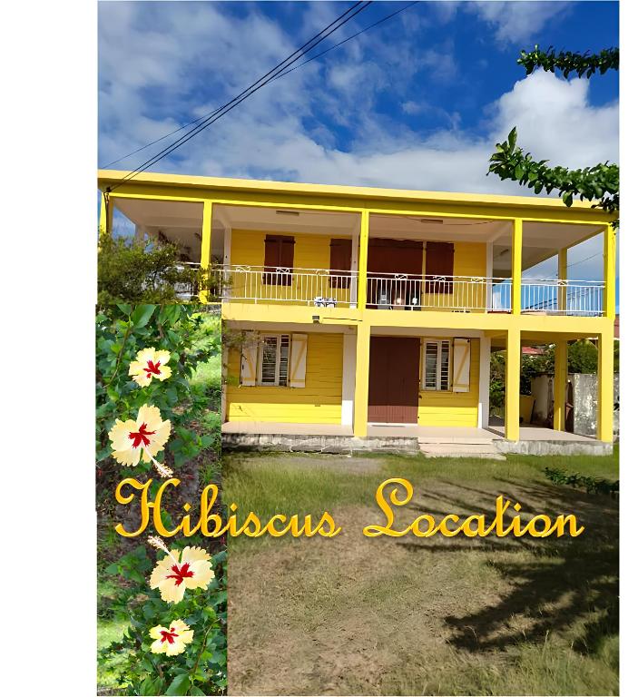 a yellow house with flowers in front of it at Hibiscus Location in Le Vauclin