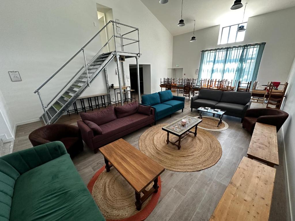un salon avec des canapés et des tables ainsi qu'un escalier dans l'établissement Le Gîte 21 - Grande Maison pour Groupes, à Vallon-Pont-dʼArc