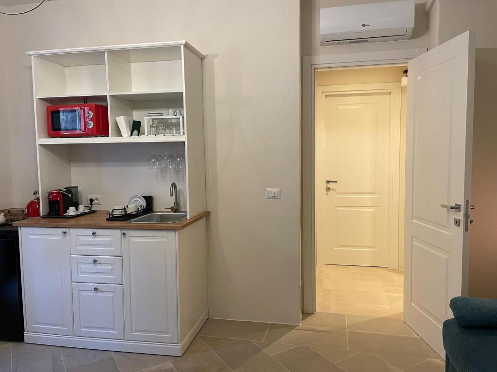a kitchen with white cabinets and a sink and a door at Castello D'Alcontres Guest House 3 stelle in Nizza di Sicilia