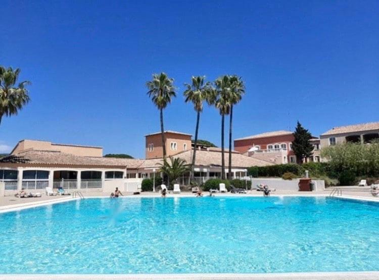 une grande piscine avec des palmiers en arrière-plan dans l'établissement Domaine de Valescure, à Saint-Raphaël