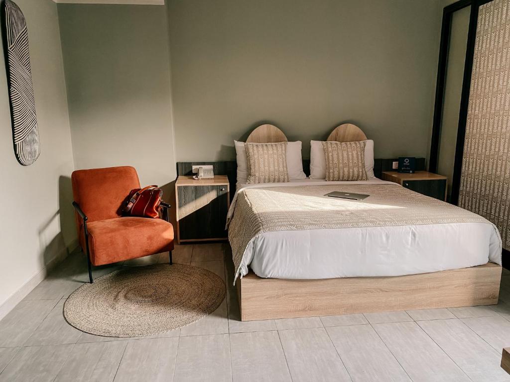 a bedroom with a bed and a red chair at ONOMO Hotel Abidjan in Abidjan