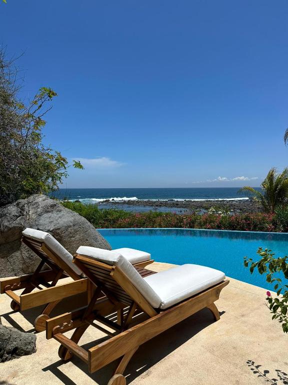 a pair of lounge chairs sitting next to a swimming pool at Casamar, beach front estate on Troncones Point in Troncones