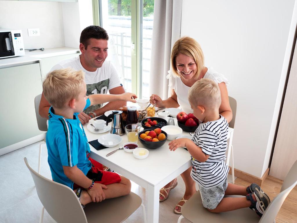 a family sitting around a table eating food at Innesti Rooms&Apartments - Gli Appartamenti in Pergine Valsugana