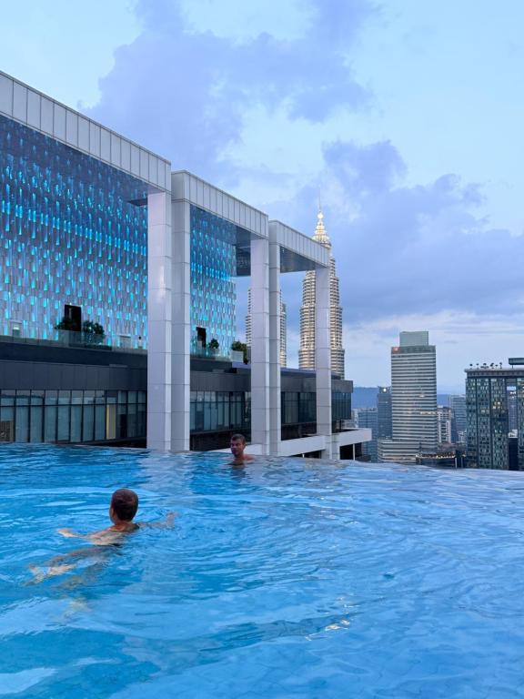 two people swimming in a swimming pool on top of a building at Platinum KLCC Suites Face in Kuala Lumpur