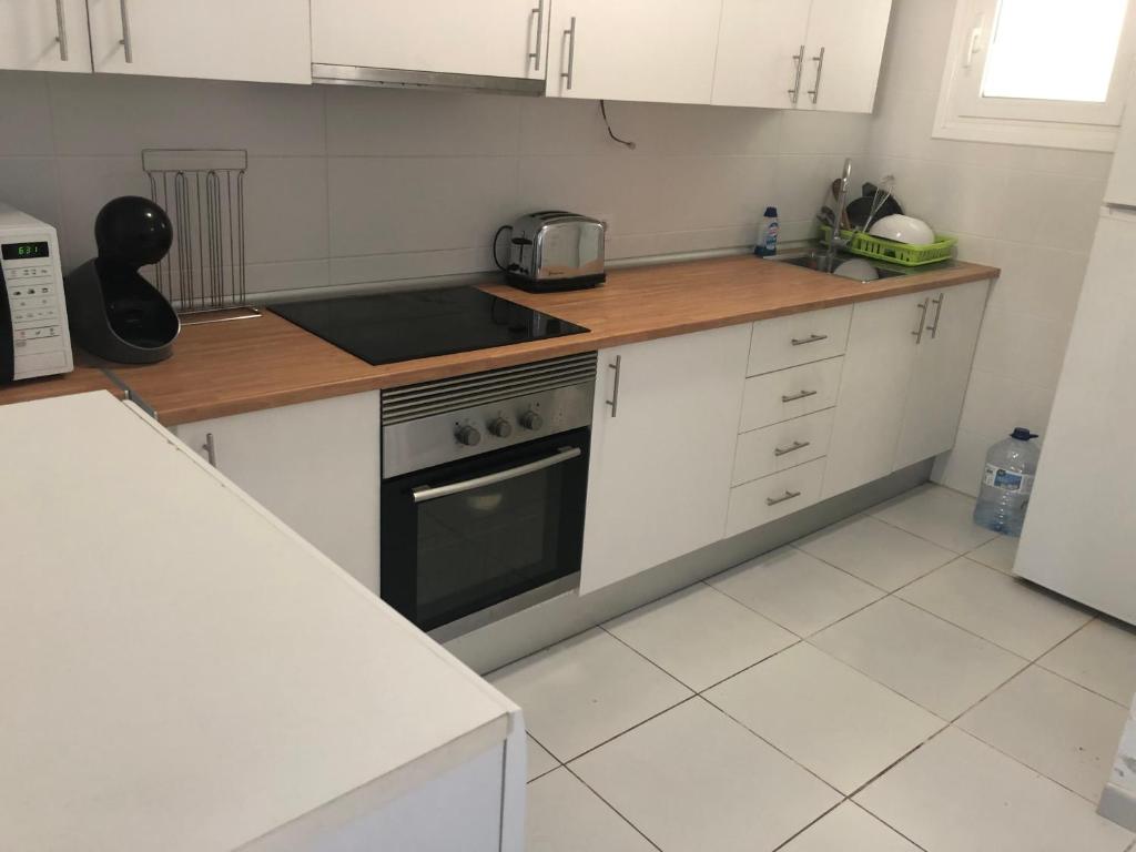 a kitchen with white cabinets and a stove top oven at Silent coast apartment in Las Galletas