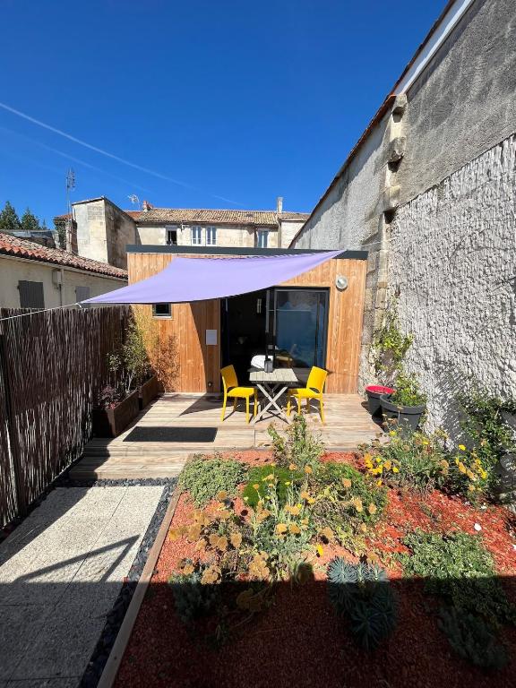 a patio with a table and chairs under a purple umbrella at L'ÉCHAPPÉE BELLE à ANGOULÊME in Angoulême
