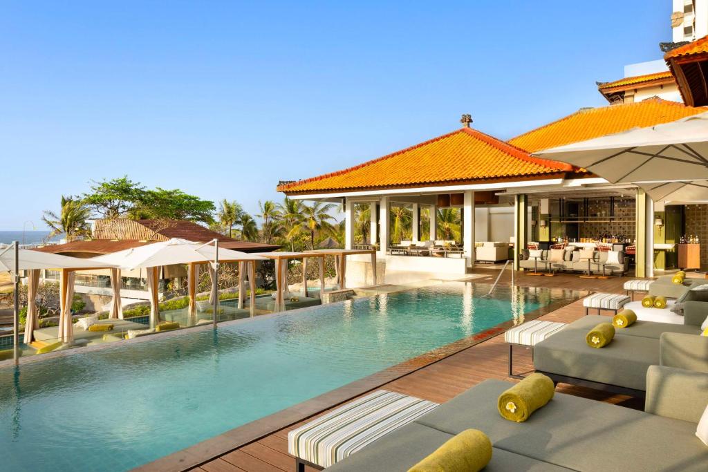 a swimming pool with lounge chairs and umbrellas at Hilton Bali Resort in Nusa Dua