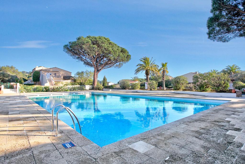 une piscine d'eau bleue et d'arbres dans l'établissement Studio Les Jardins du Pinet - Happy Rentals, à Saint-Tropez