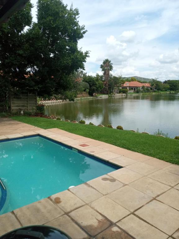 a swimming pool in front of a lake at Pecanwood Estate Cosy home 3 bedrooms with pool in Hartbeespoort