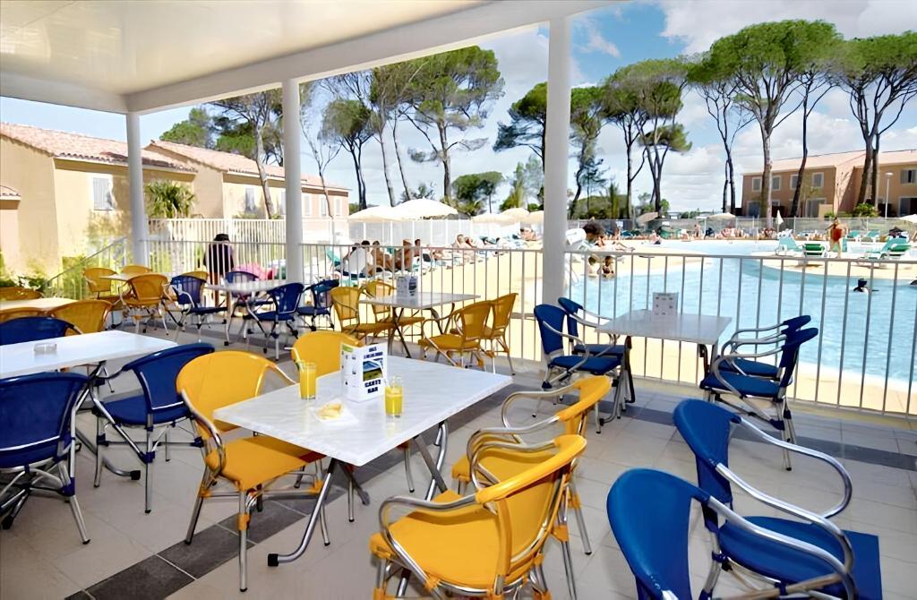 patio ze stołami i krzesłami obok basenu w obiekcie Maison accueillante à Calvisson avec piscine et terrasse w mieście Calvisson