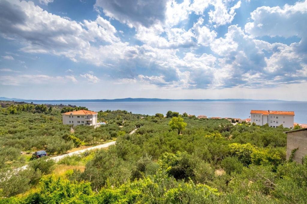 a view of three houses on a hill next to the water at Apartment Damir in Tučepi