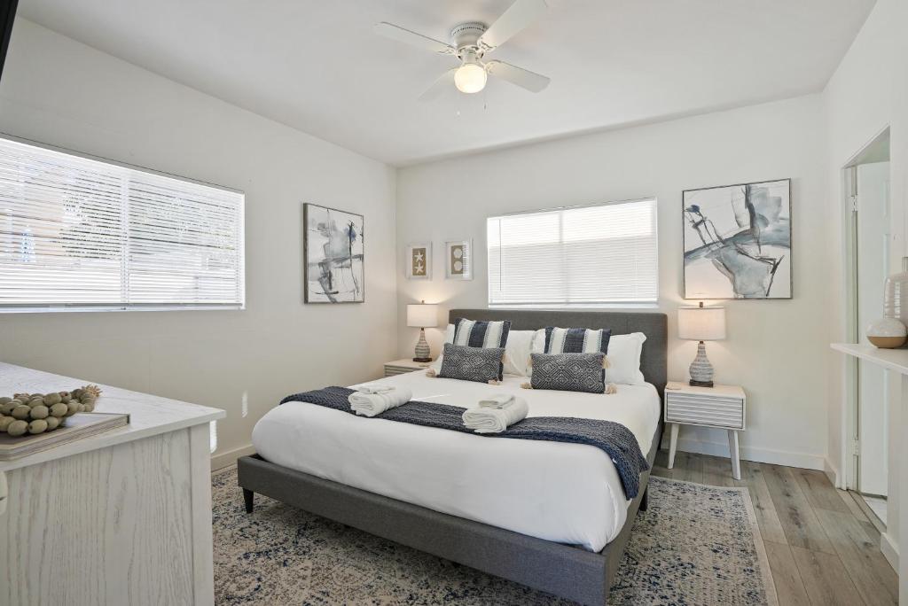 a white bedroom with a large bed and two windows at Draper Bungalow By CoastVH - Charming 1940 in San Diego