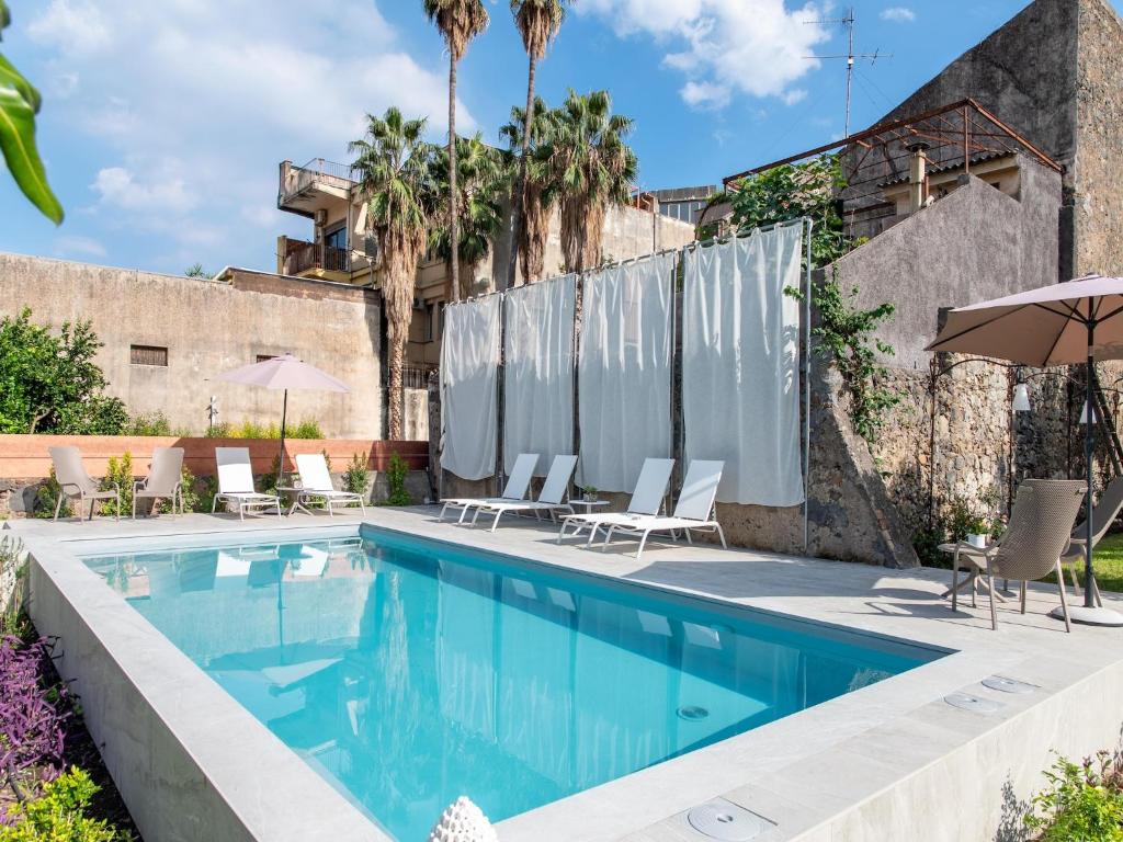 a swimming pool with chairs and umbrellas next to a building at Apartment in Giarre near Mount Etna in Giarre
