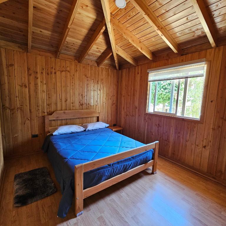 1 dormitorio con 1 cama en una cabaña de madera en Cabañas Los Arrayanes, en Licán Ray