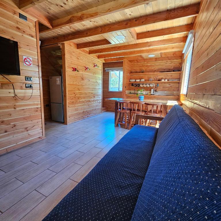 una sala de estar con una cama azul en una cabaña de madera en Cabañas Los Arrayanes, en Licán Ray