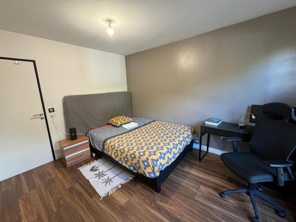 a bedroom with a bed and a desk and a chair at Stade de France Chambre d'Hôte by RESERVATI HOME in Saint-Denis