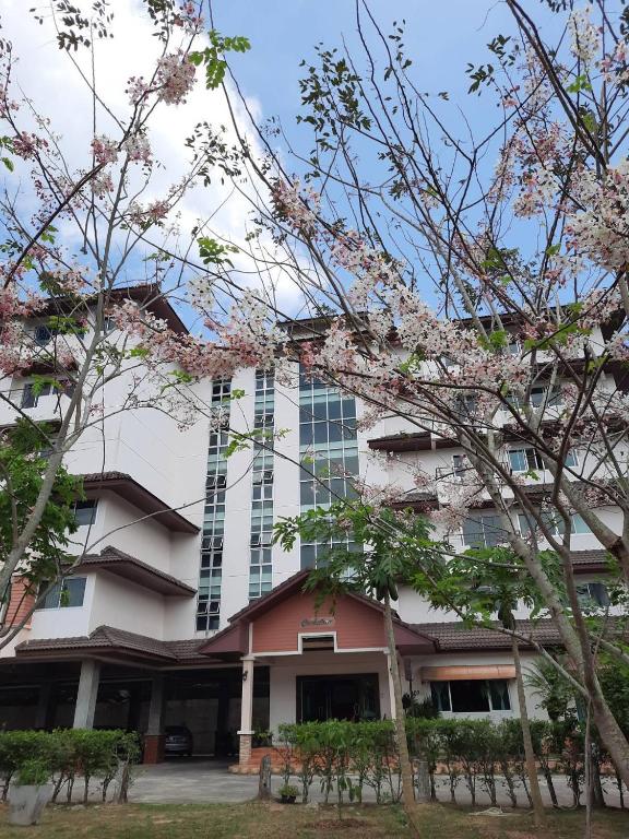 a building with flowering trees in front of it at Ingfah Mountainview in Hat Yai