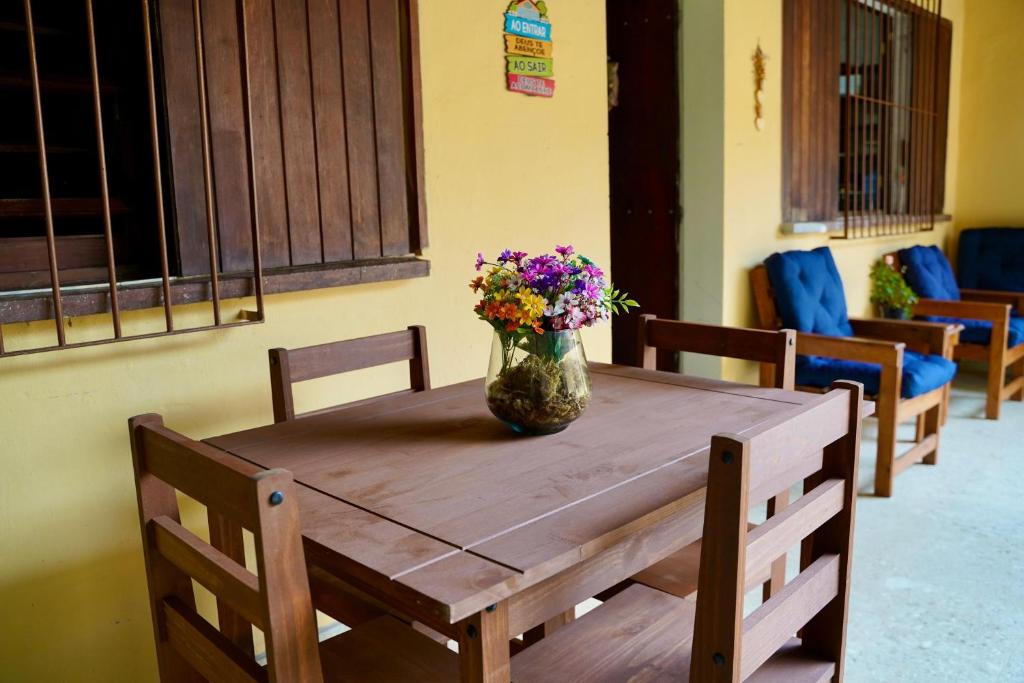 a wooden table with a vase of flowers on it at Pousada Villa Bella in Maricá