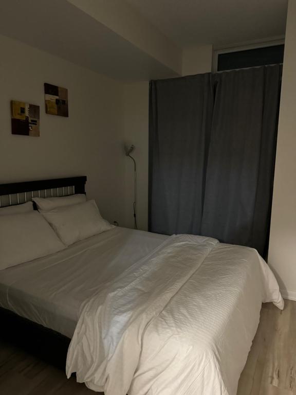 a bedroom with a large white bed and a window at A lovely one bed room with Sunset Views in Toronto