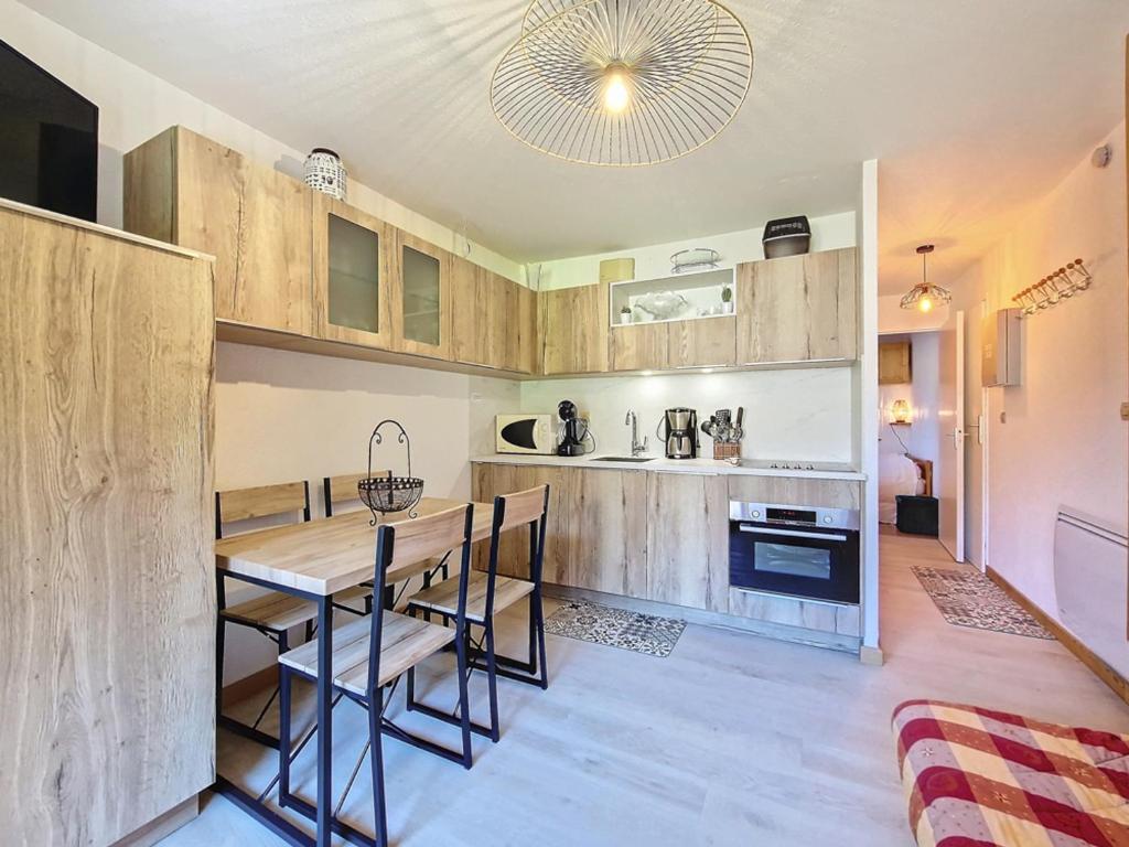 une cuisine avec une table et des chaises et une cuisine avec un comptoir dans l'établissement Appartement cosy La Clusaz - 4 pers., parking, balcon, 2* - FR-1-818-17, à La Clusaz