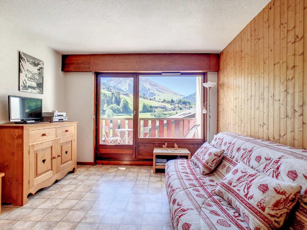 un salon avec un canapé et une grande fenêtre dans l'établissement Appartement cosy pour 6 pers à La Clusaz, 2 chambres, wifi, proximité pistes - FR-1-818-75, à La Clusaz