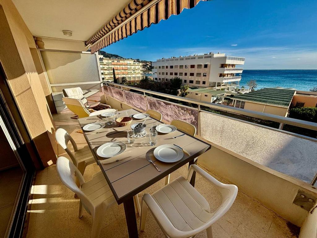 un balcon avec une table et des chaises et l'océan dans l'établissement Appartement lumineux avec terrasse et accès plage - FR-1-816-15, au Lavandou