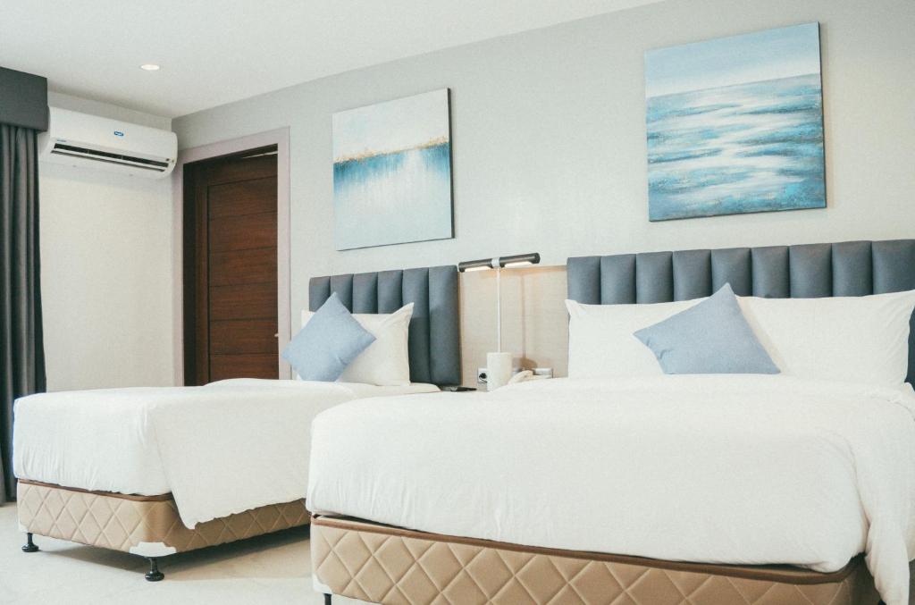 two beds in a bedroom with white and blue at NS Royal Hotel in Cebu City