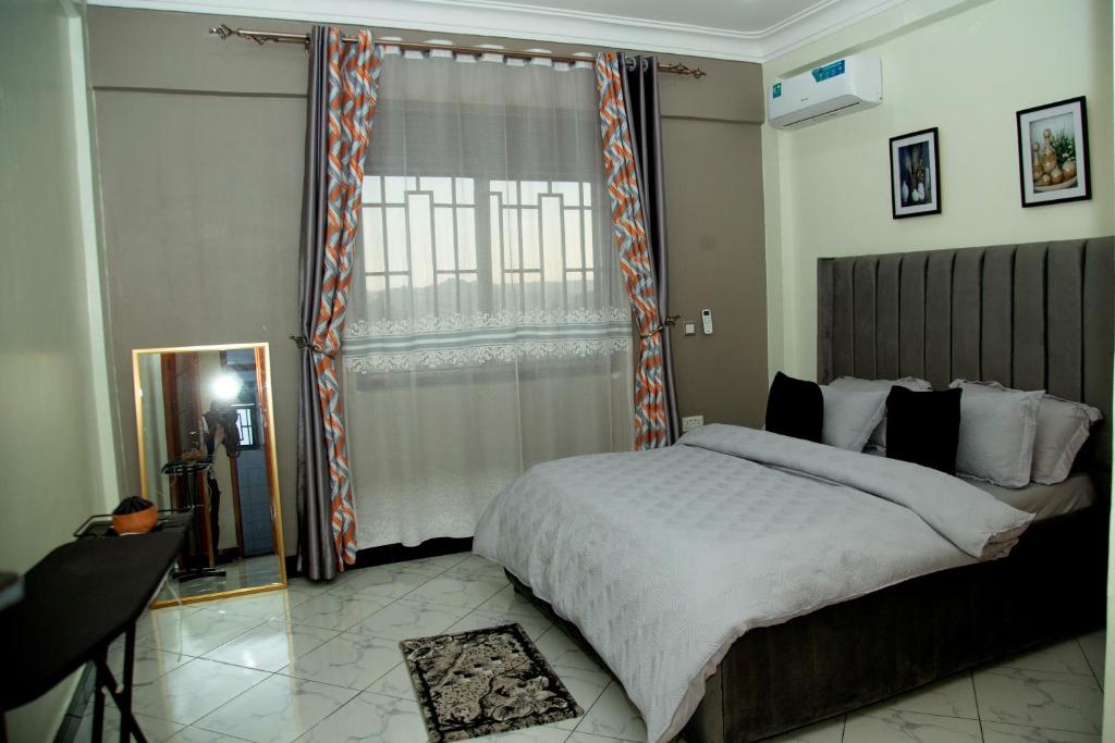 a bedroom with a large bed and a window at The Vault Heights Apartments in Kampala