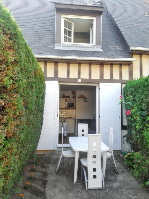 une terrasse avec une table et des chaises dans un garage dans l'établissement Appartement charmant à Villers-sur-Mer, 30 m², avec terrasse, à Villers-sur-Mer