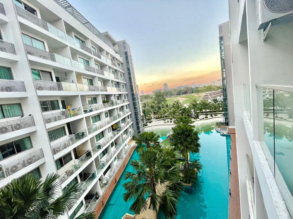 an apartment building with a swimming pool and palm trees at Laguna Beach 1 Condo&Resort Pattaya Bey Aey in Jomtien Beach