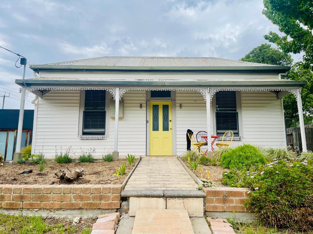 a small white house with a yellow door at Updated Cottage on Large Sunny Block - 5 mins-CBD in Canadian