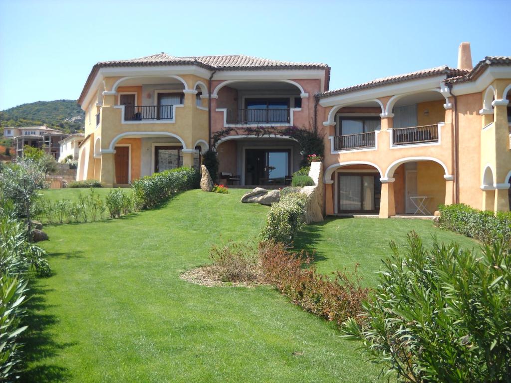 uma casa grande com um relvado verde em frente em Trilocale I Meridiani Le Maree 4T em Cannigione